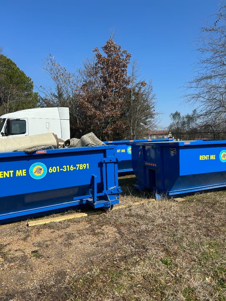 Mid South Dumpster Rentals delivery truck dropping off a roll-off dumpster